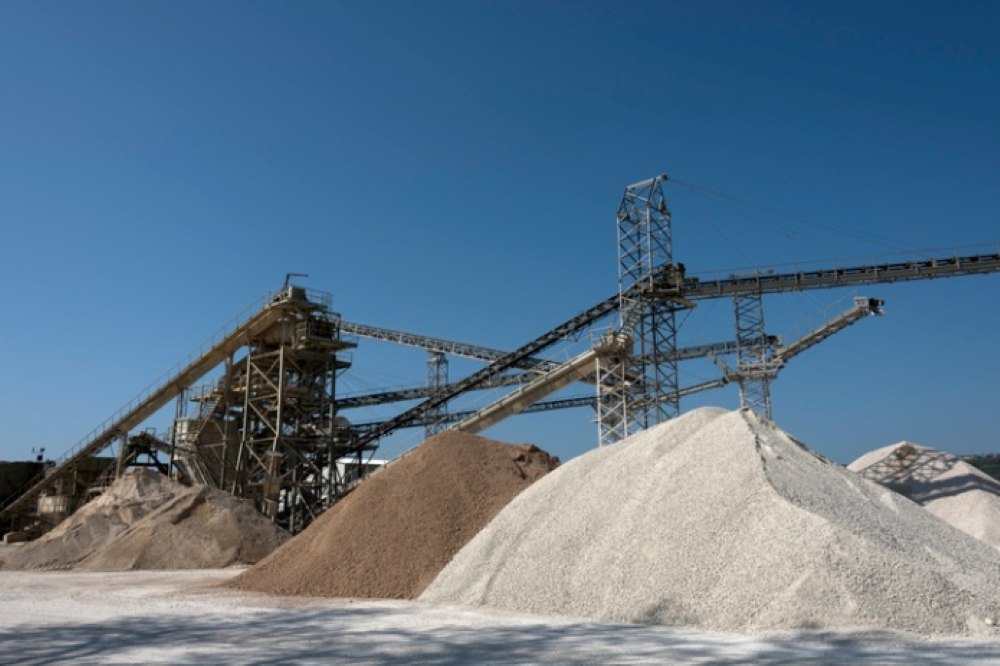 Aggregate processing plant with conveyor systems and gravel stockpiles under clear sky
