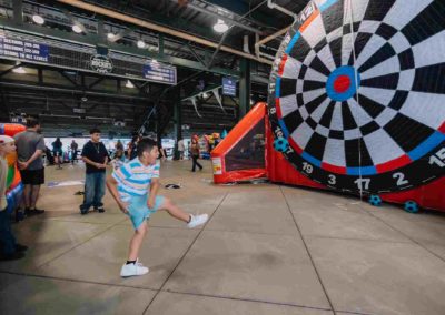 Child kicking a ball at the giant dart game at the Brannan Company Picnic 2025 in Colorado