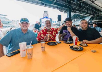 A group of people is posing while eating at the Brannan Companies' picnic in Denver, CO.