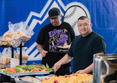 Two people are serving food during the Brannan Companies picnic event in Denver, CO